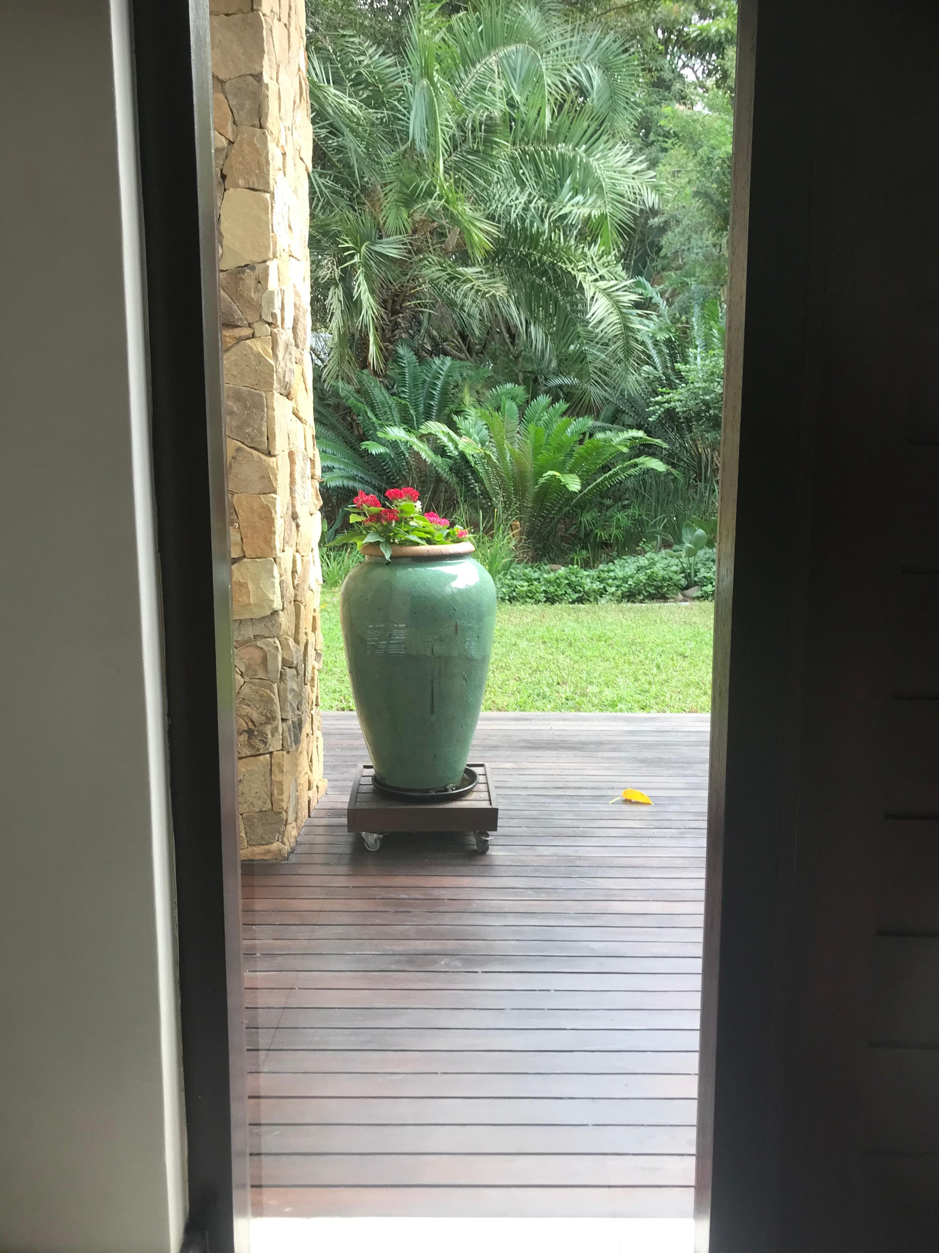 Ceramic pot with flowers on wooden deck with tropical backdrop