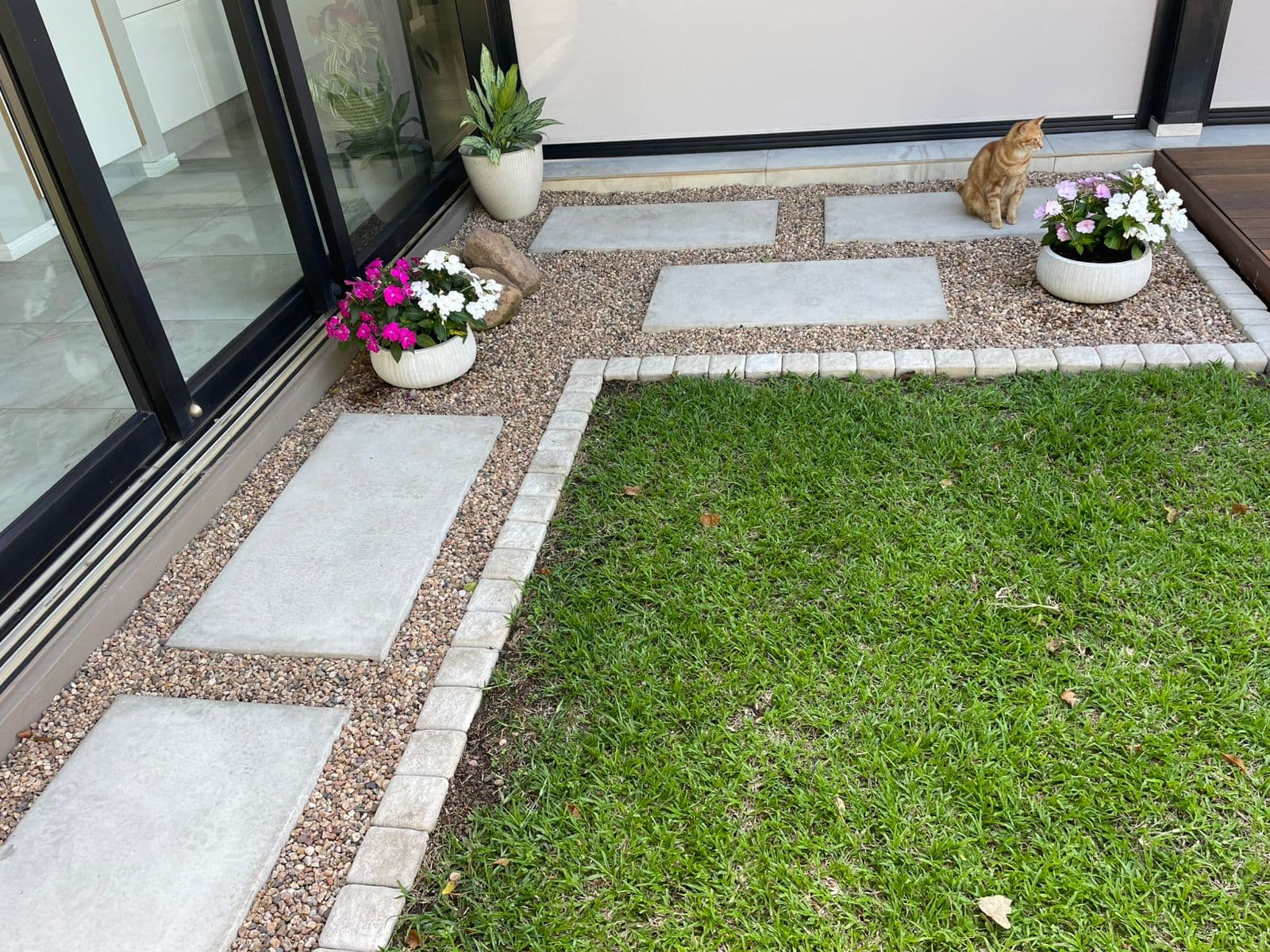 Garden patio with stepping stones, lawn and potted flowers