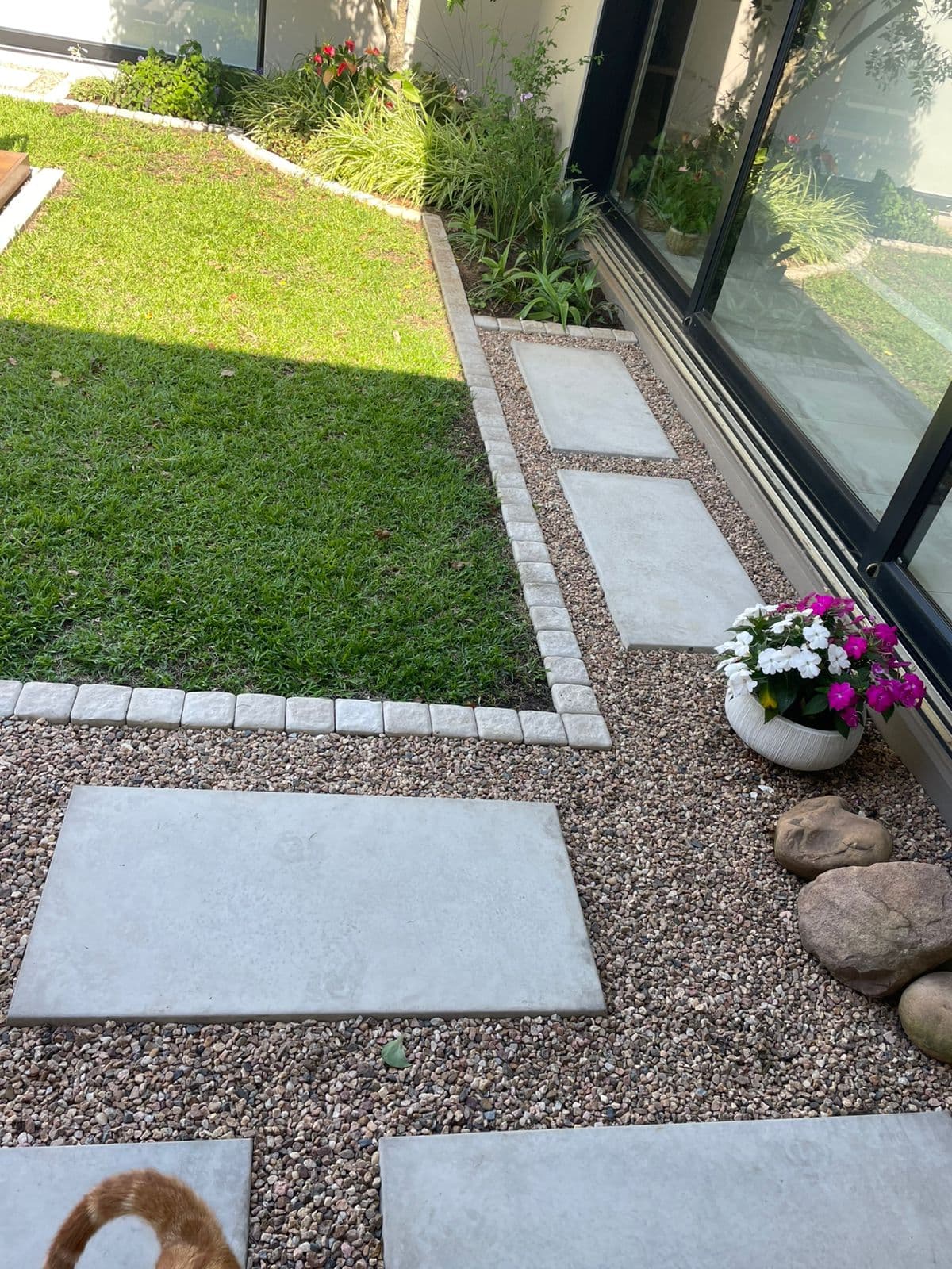 Modern stepping stones with cobblestone edging alongside lawn