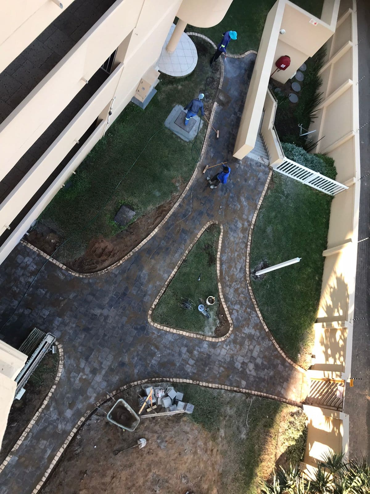 Aerial view of curved cobblestone pathway with brick edging being laid